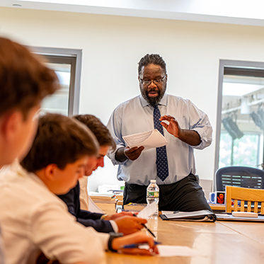 A teacher instructing students in class. Links to Gifts That Pay You Income